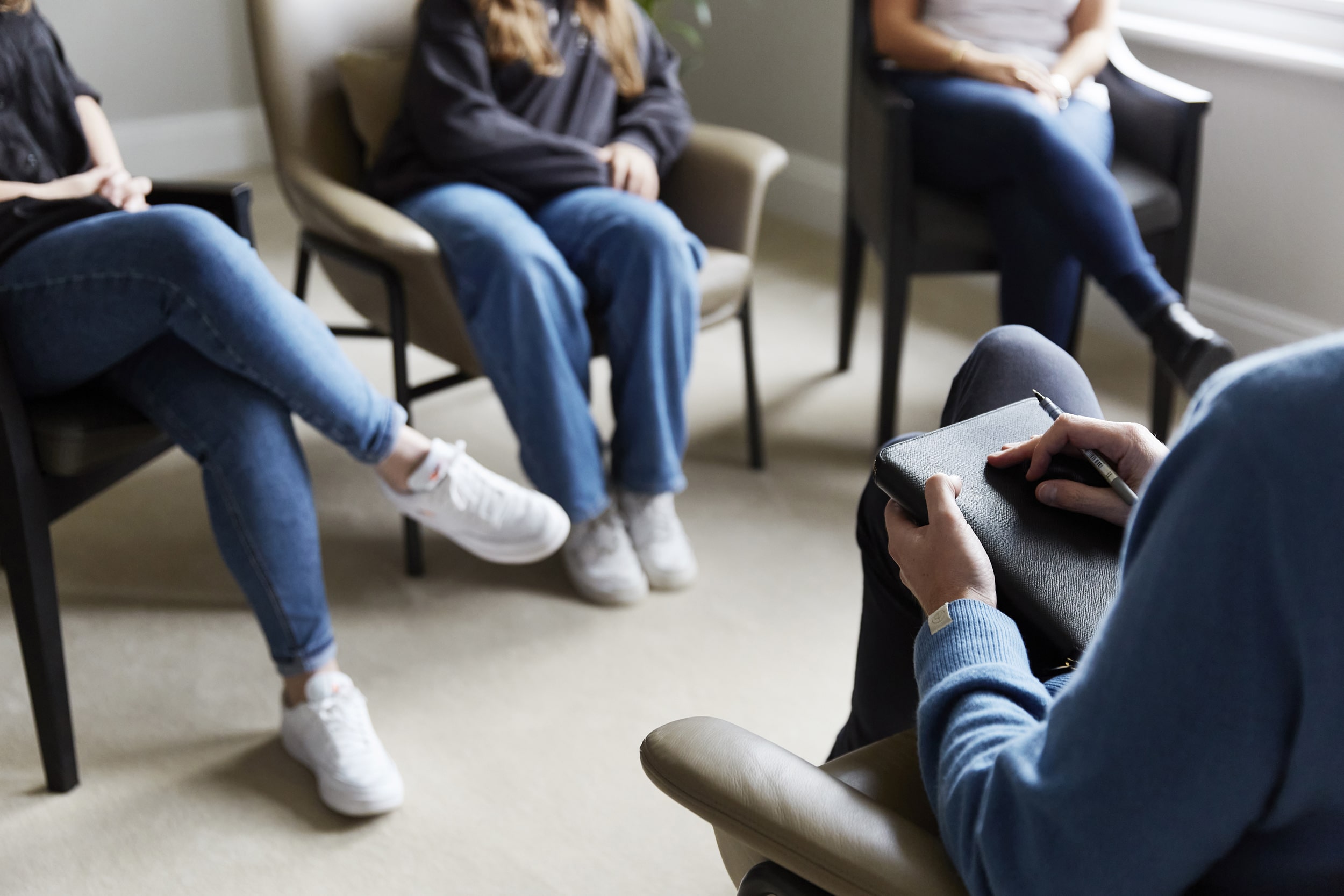 Group therapy session at The Chelsea Psychology Clinic in London, with participants seated in comfortable chairs and openly discussing mental health support in a relaxed environment.